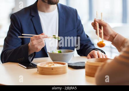 Man enjoying Asian food during business lunch with colleague at shopping mall cafe, closeup Stock Photo