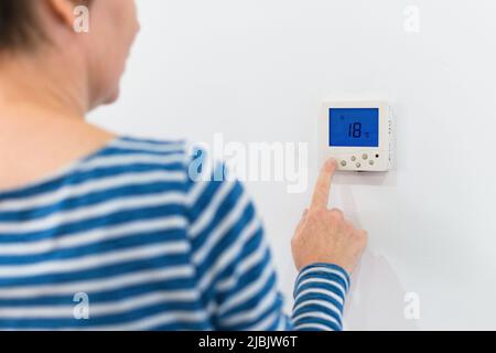 Female hand using of home heating and cooling system control unit, selective focus Stock Photo