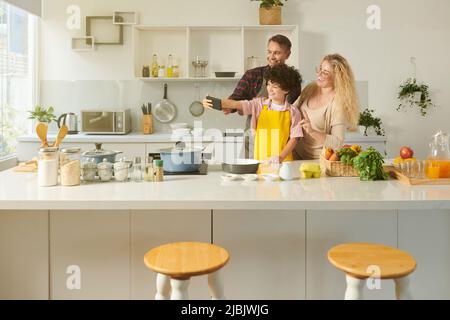 Joyful preteen boy taking selfie with parents when they are cooking together Stock Photo