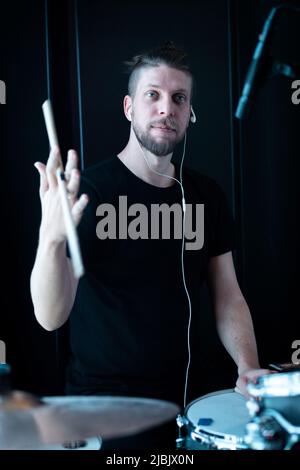 A young drummer in a recording studio plays drums sounded by microphones Stock Photo
