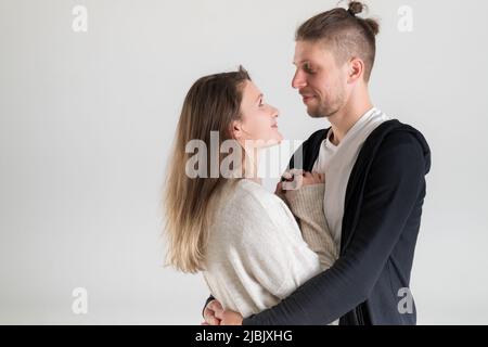 Portrait of a young caucasian couple of lovers hugging and looking at each other on a white background Stock Photo
