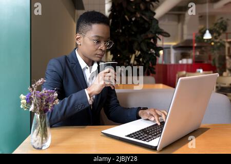 Serious and focused business woman working in a hotel restaurant, African American woman traveling on a business trip Stock Photo