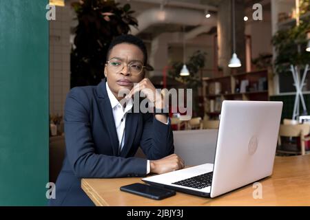 Young business woman working is a cafe with a laptop, African-American is focused on the end of the project, the deadline is for lunch break Stock Photo