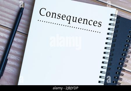 Consequences word written on notepad on wooden desk. Negative, positive, bad and good result concept. Stock Photo