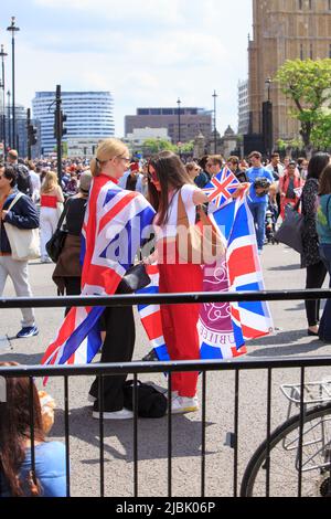 Westminster, London, 2022.  Revellers enjoying the Bank Holiday Weekend in London, wrapped in Union Jack Flags. Stock Photo