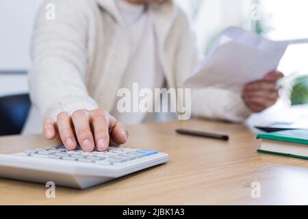Man using calculator at wooden table Stock Photo