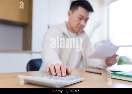 Man using calculator at wooden table Stock Photo