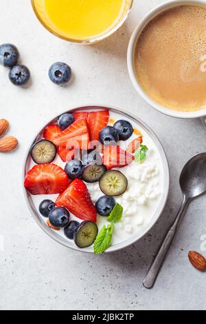 Cottage cheese with strawberries, nuts and blueberries in a gray bowl for breakfast, top view. Summer recipe. Stock Photo