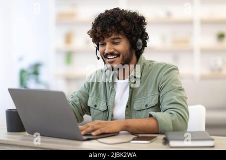 Positive handsome indian guy working online, having video conference Stock Photo