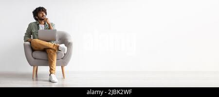 Pensive indian guy with computer on lap over white background Stock Photo