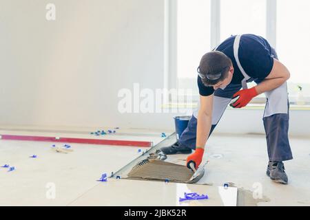 A male construction worker installs a large ceramic tile Stock Photo