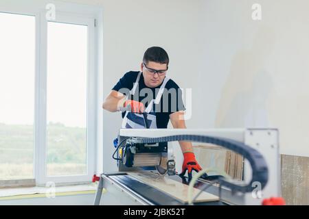 Master man, builder cuts a tile. Machine with a circular saw Stock Photo