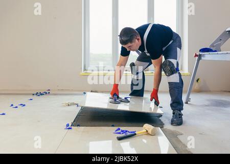 A male construction worker installs a large ceramic tile Stock Photo