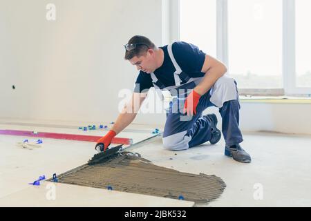 A male construction worker installs a large ceramic tile Stock Photo