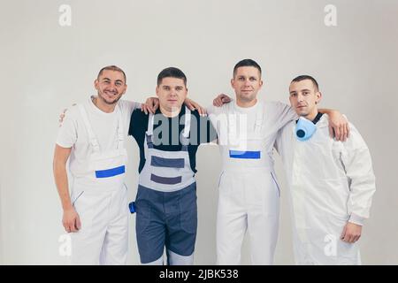 A team of construction workers, four people, men performing construction and repair work looking into the camera Stock Photo