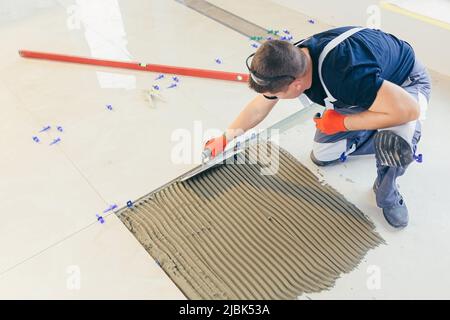 A male construction worker installs a large ceramic tile Stock Photo