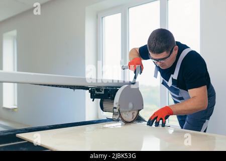 Master man, builder cuts a tile. Machine with a circular saw Stock Photo