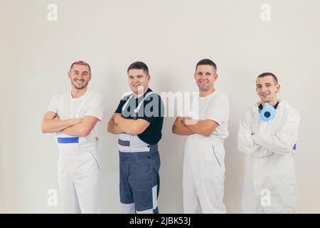 A team of construction workers, four people, men performing construction and repair work looking into the camera Stock Photo