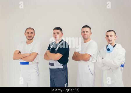 A team of construction workers, four people, men performing construction and repair work looking into the camera Stock Photo