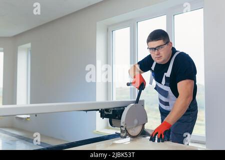 Master man, builder cuts a tile. Machine with a circular saw Stock Photo