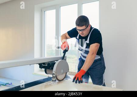Master man, builder cuts a tile. Machine with a circular saw Stock Photo