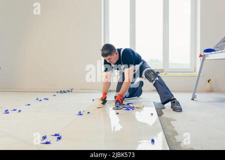 A male construction worker installs a large ceramic tile Stock Photo