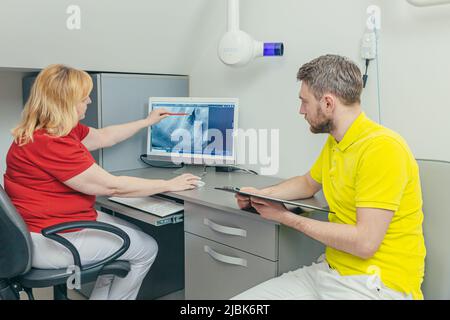Meeting of dentists. doctors and assistants examine the X-ray of the patient's teeth and jaws on the computer, discuss treatment in the office Stock Photo