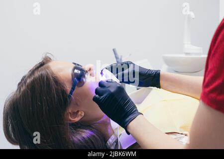 Close-up a dentist with an assistant treats the woman's teeth, the patients face is closed Stock Photo