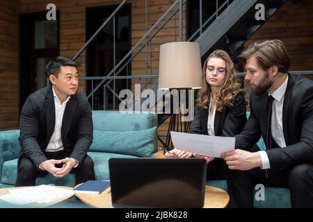 Three multiethnic businessmen consider a business contract offer in the field of IT technologies and the provision of legal consulting services using Stock Photo