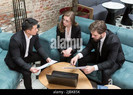 Three multiethnic businessmen consider a business contract offer in the field of IT technologies and the provision of legal consulting services using Stock Photo