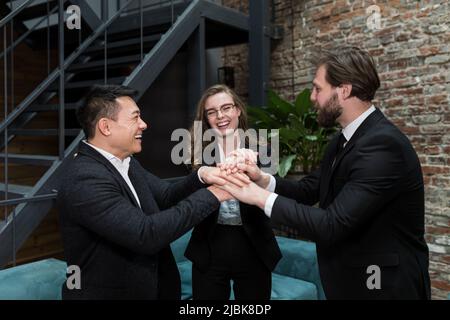 The team of employees hold hands together, rejoice in the work done, and overcome difficulties, the team successfully works together Stock Photo