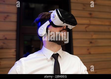 A man office manager in formal clothing wearing virtual reality vr glasses swiping scrolling online images in modern office. Augmented reality concept Stock Photo