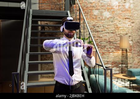 A man office manager in formal clothing wearing virtual reality vr glasses swiping scrolling online images in modern office. Augmented reality concept Stock Photo