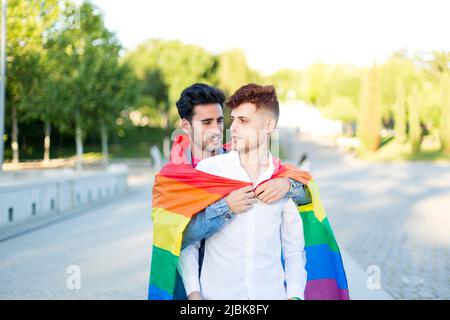 Gay couple embracing with LGBT pride flag outdoors. Relationship ...