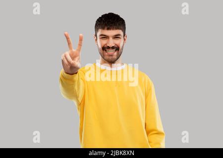 young man showing peace over grey background Stock Photo