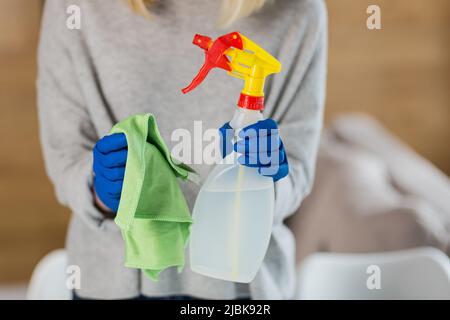 Close up photo hands of young woman in rubber gloves holding rag and detergent clean Stock Photo