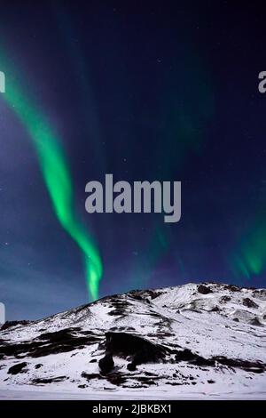 Aurora Borealis seen over a snow covered hill in Iceland Stock Photo