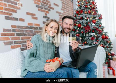 Happy family received confirmation of credit and money on bank account, on credit card, rejoice at home sitting on sofa during New Year and Christmas Stock Photo