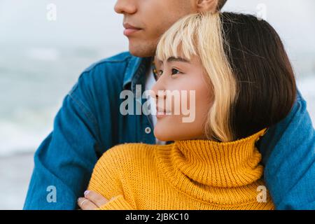 Multiracial young couple hugging while walking on beach Stock Photo