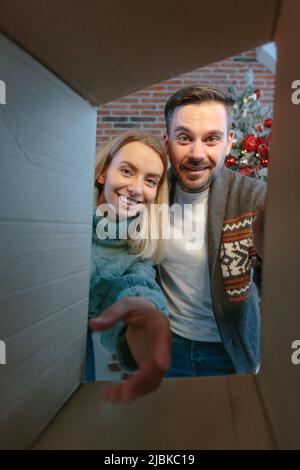 Young beautiful happy couple joyfully open packages of boxes with gifts for New Year and Christmas in love and happy Stock Photo