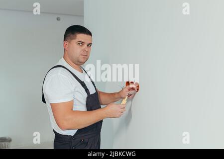 Male worker professional electrician installs electrical outlet in apartment after repair Stock Photo
