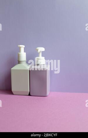 Plastic shampoo bottles on purple table. purple wall background Stock Photo