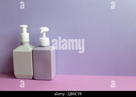 Plastic shampoo bottles on purple table. purple wall background Stock Photo