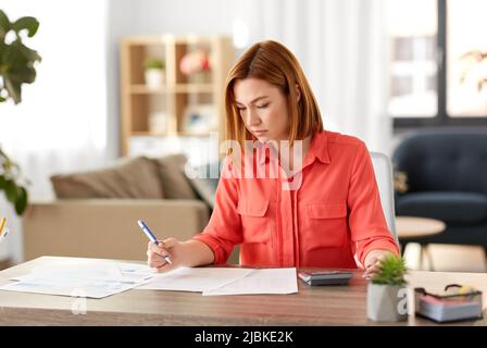woman with calculator and papers working at home Stock Photo