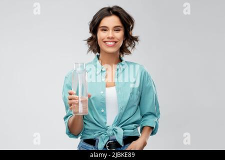 smiling young woman holding water in glass bottle Stock Photo