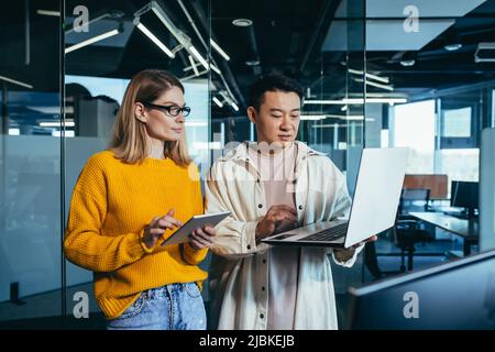Brainstrom business team is responsible for solving the tasks, employees colleagues Asian man and woman work together in a modern office, look at the Stock Photo