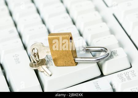 An unlocked padlock on top a computer keyboard to represent the concept of computer security breach Stock Photo