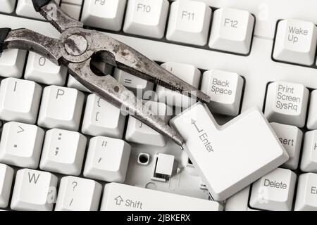 Pliers with ENTER key removed  from a keyboard laying on the keyboard. Close up view. Stock Photo