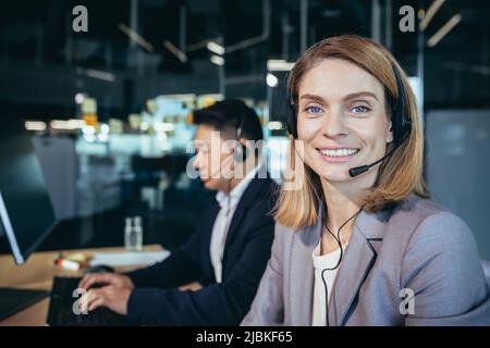 call center employee provide help to client distantly. Asian male customer services agent with headset working in online store helpline, smiling and t Stock Photo