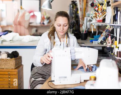 Young woman sewer working with modern sewing machine Stock Photo